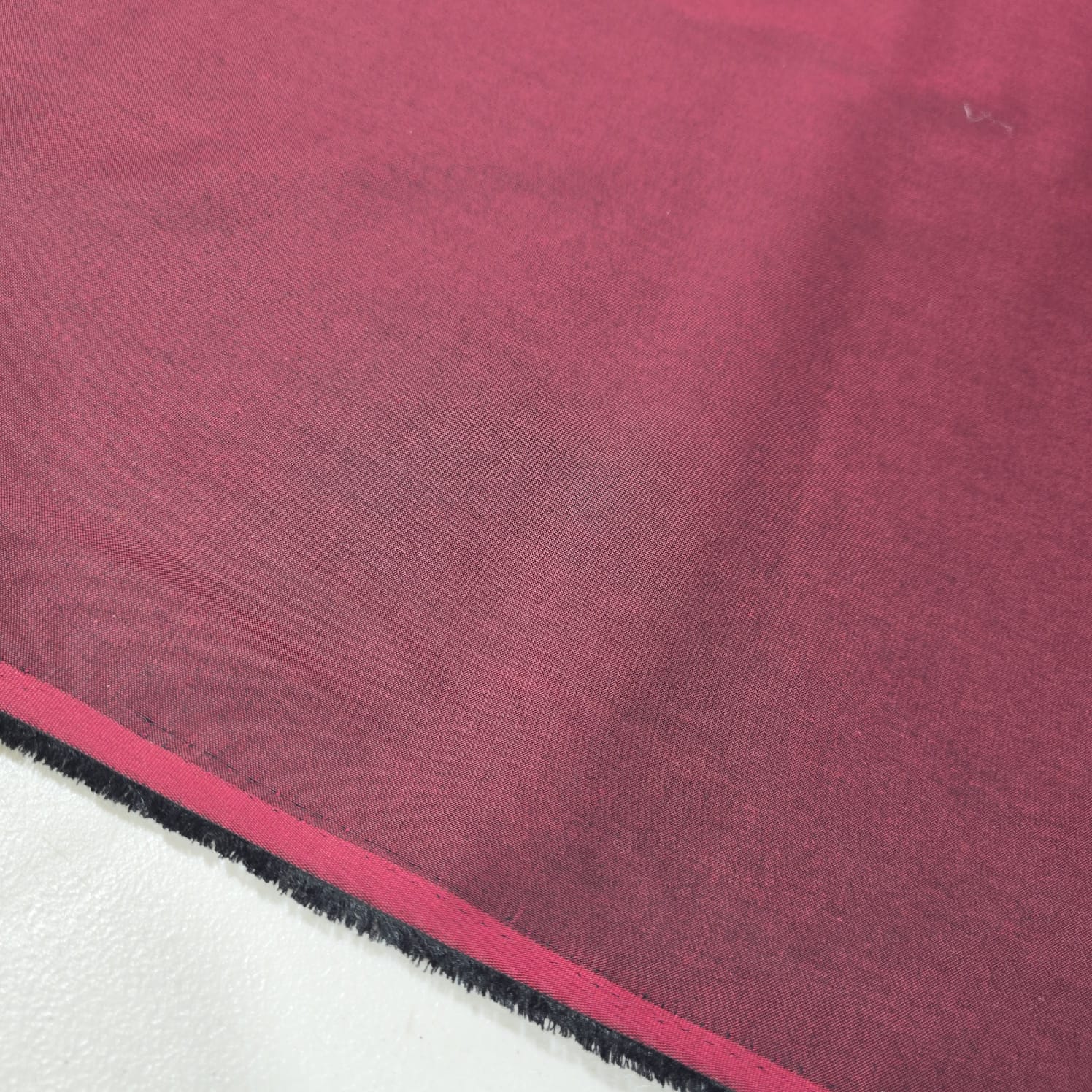 Burgundy 100% cotton chambray fabric draped to showcase its soft lightweight woven texture, 58-inch wide dressmaking fabric sold by the metre.