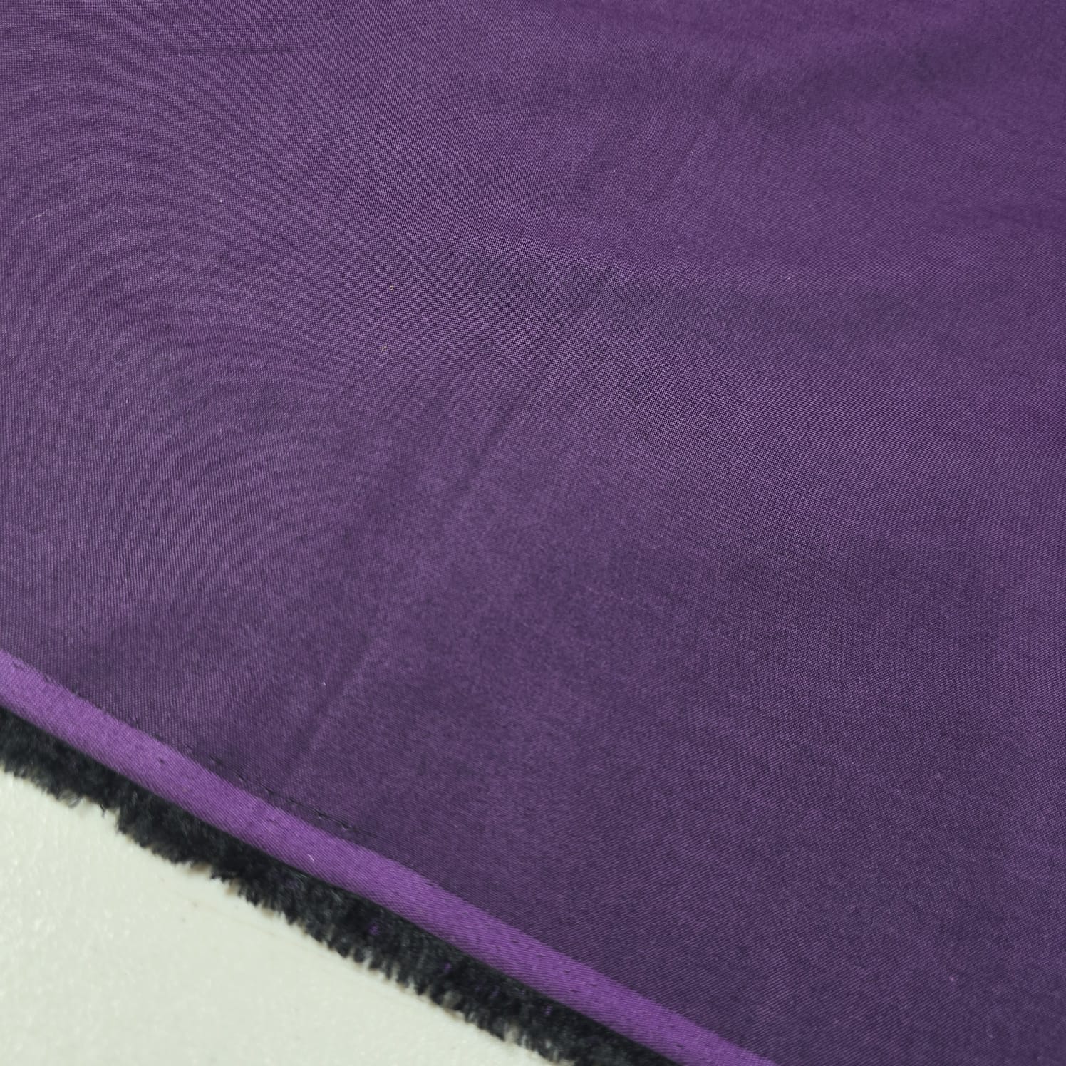 Purple 100% cotton chambray fabric draped to showcase its soft lightweight woven texture, 58-inch wide dressmaking fabric sold by the metre.